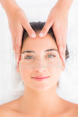 Attractive young woman receiving head massage at spa center