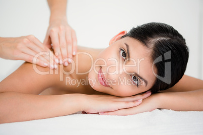 Pretty brunette enjoying a massage smiling at camera