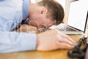 Stressed businessman with head on laptop