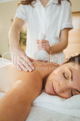 Young woman getting herbal compress massage