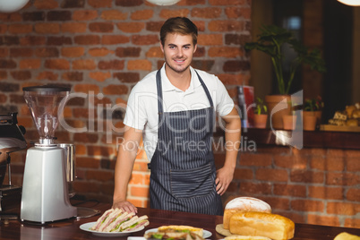 Handsome waiter bended over a food table