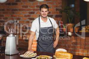 Handsome waiter bended over a food table