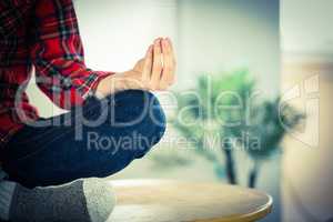 Hipster businessman meditating at his desk