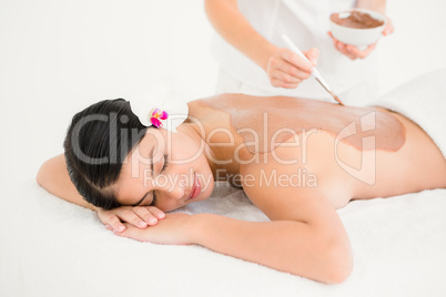 Woman lying on massage table getting mud treatment