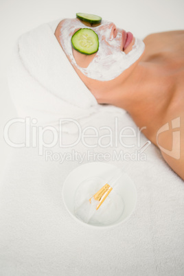 Relaxed woman with cucumber on a creamed face