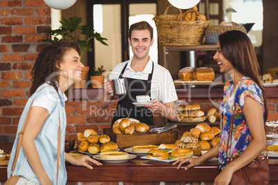 Pretty customers laughing in front of smiling barista