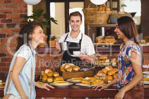 Pretty customers laughing in front of smiling barista