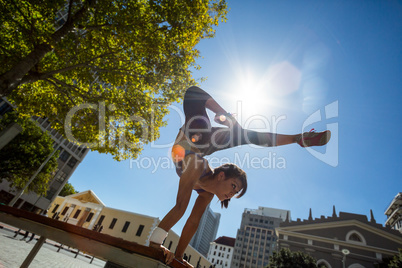 Athletic woman performing handstand on bench