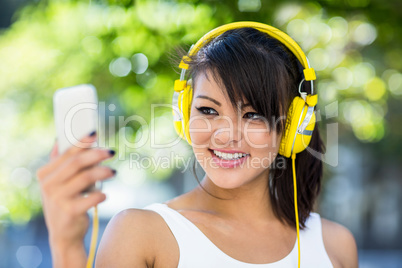 Smiling athletic woman wearing yellow headphones and taking self