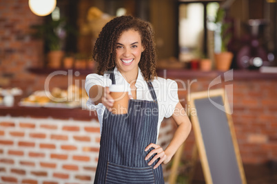 Smiling barista handing a mug of coffee