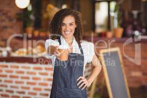 Smiling barista handing a mug of coffee