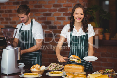 Pretty waitress picking a sandwich