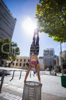 Athletic woman performing handstand on bin