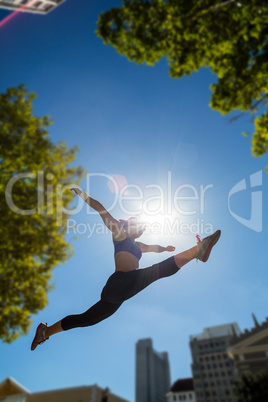 Athletic woman jumping in the air and doing split