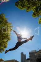 Athletic woman jumping in the air and doing split
