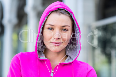 Portrait of a woman wearing a pink jacket putting her headphones