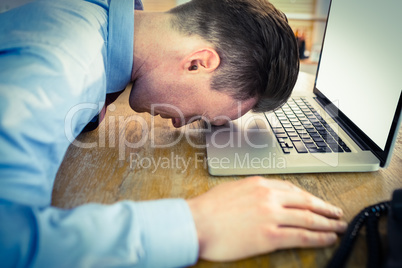 Stressed businessman with head on laptop