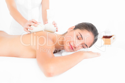 Beautiful brunette enjoying a herbal compress massage