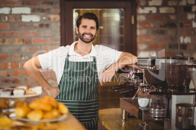 Smiling barista leaning on the coffee machine