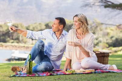 Smiling couple sitting on picnic blanket and enjoying the view