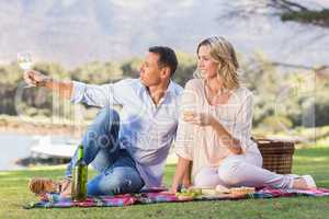 Smiling couple sitting on picnic blanket and enjoying the view