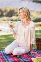 Smiling blonde woman sitting on picnic blanket