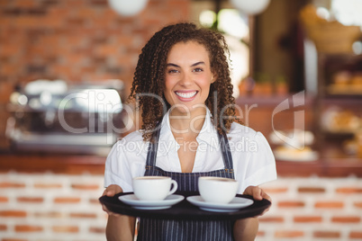 Smiling barista holding a tray of coffee cups