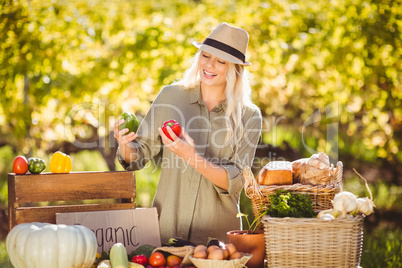 Smiling blonde holding red and green peppers