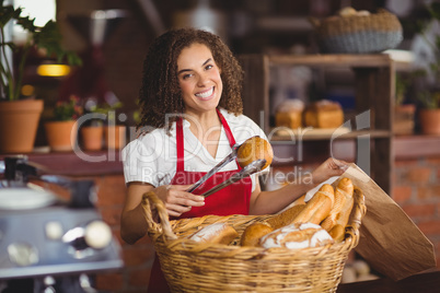 Smiling waitress picking up bread from a basket