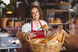Smiling waitress picking up bread from a basket