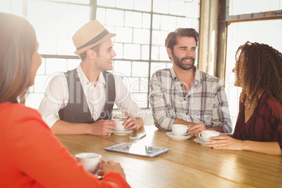 Smiling friends talking and having coffee together