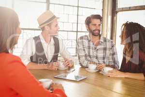 Smiling friends talking and having coffee together