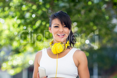 Portrait of smiling athletic woman wearing yellow headphones and