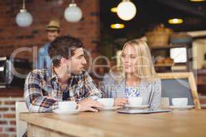 Two smiling friends talking and drinking coffee