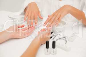 Beautician filing female clients nails at spa beauty salon