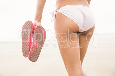 Fit woman in bikini holding flip flops