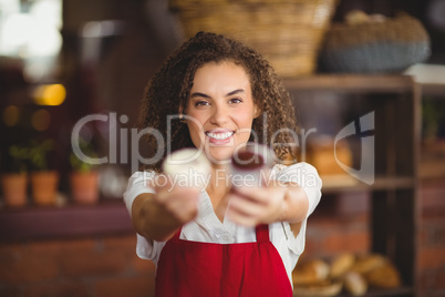 Smiling waitress showing two cupcakes