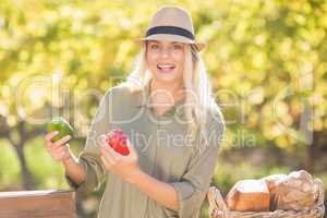Smiling blonde holding red and green peppers