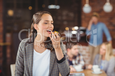 Smiling young woman eating muffin