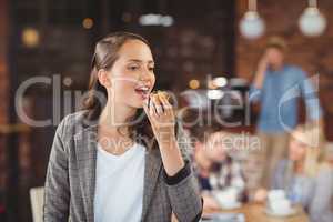 Smiling young woman eating muffin
