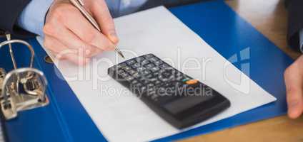 Businessman using a calculator and writing