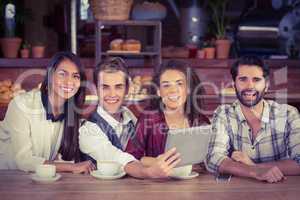 Smiling friends holding a digital tablet