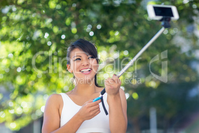 Smiling athletic woman taking selfies with selfiestick