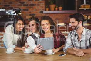 Smiling friends looking at digital tablet