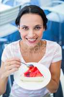 Smiling brunette taking a piece of chocolate cake