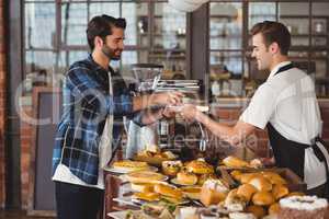 Smiling hipster getting cup of coffee from barista