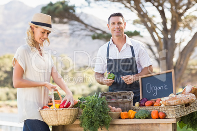 Smiling farmer selling red and green peppers