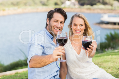 Cute couple on date handing red wine glasses