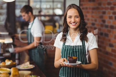 Pretty waitress holding a plate with muffin