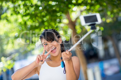 Smiling athletic woman taking selfies with selfiestick